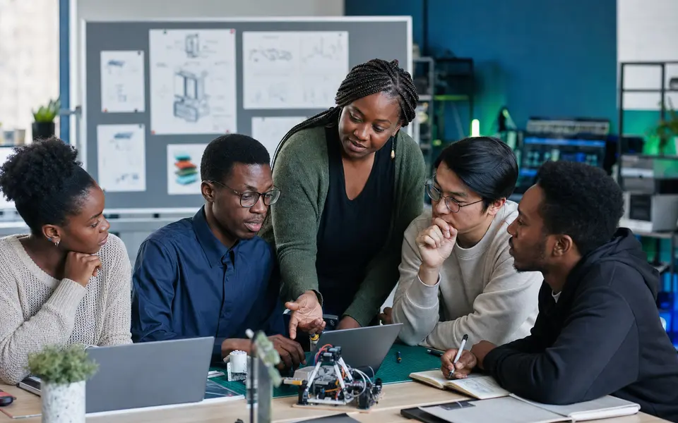 African educator guiding diverse adult learners through a practical AI project review